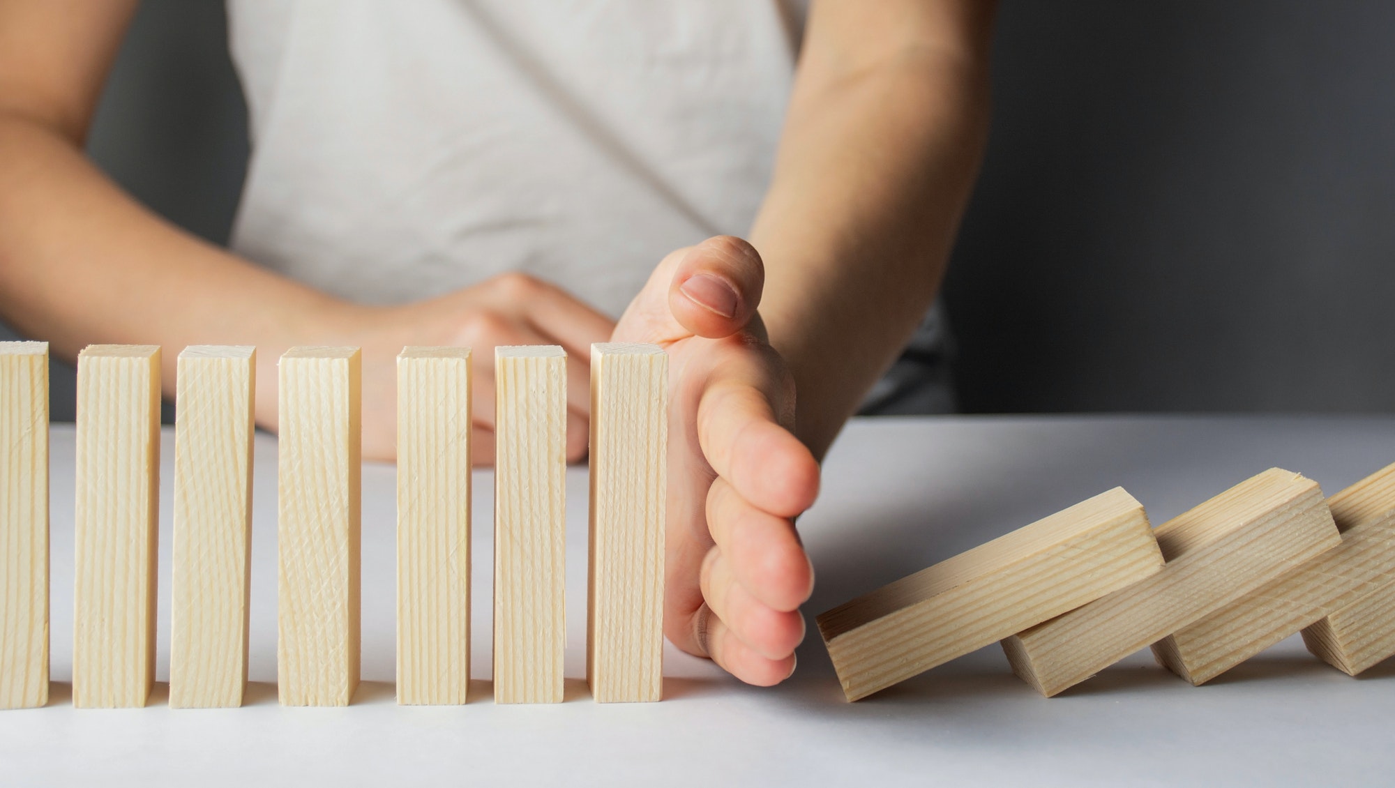 Business concept. Business destruction. Businessman stops the domino effect. Risk management.